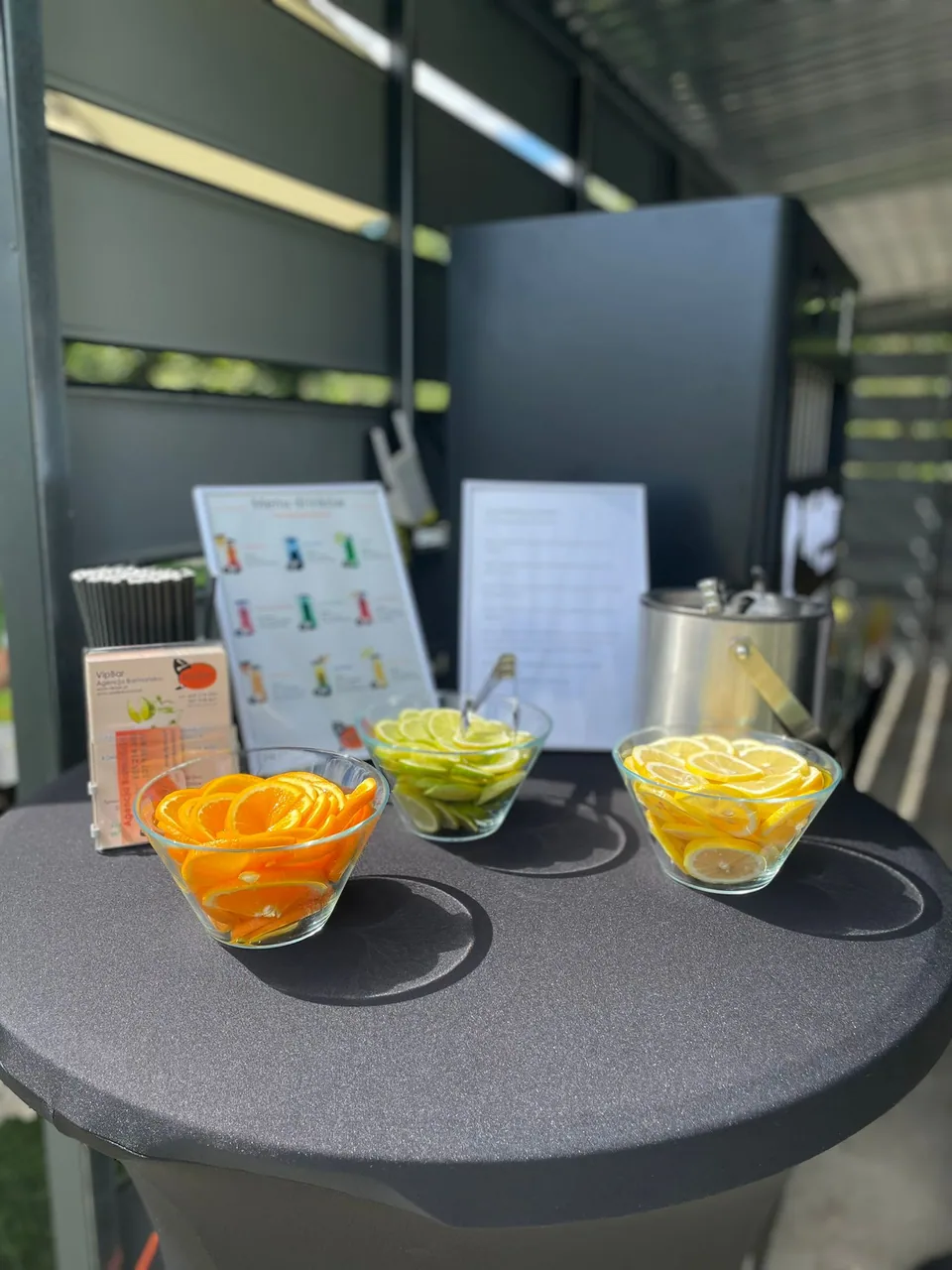Miseczki z cytrusami i karta menu na czarnym stoliku przy urządzeniu