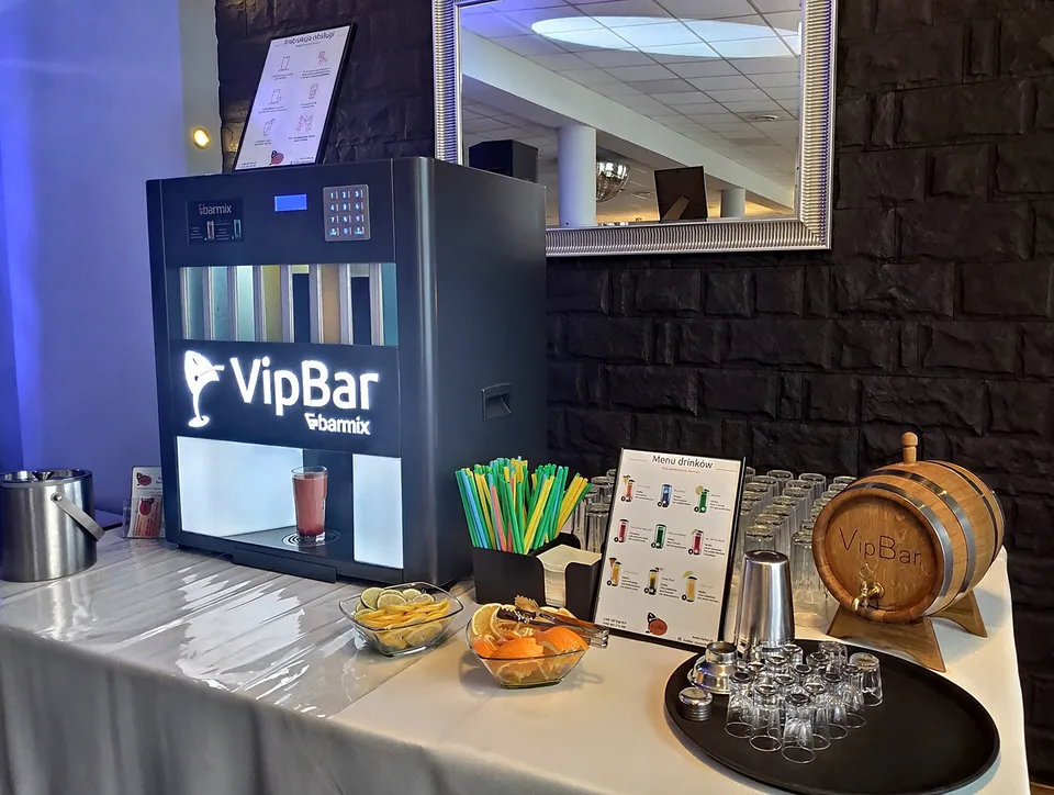 Automatyczny barman z menu, cytrusami i szklankami na tle ciemnej ściany