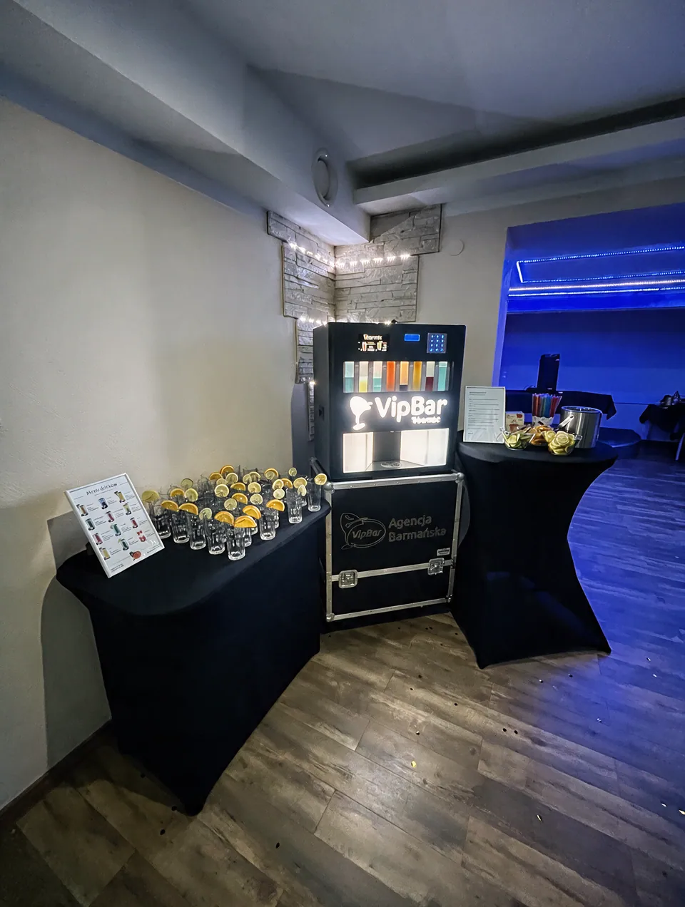 Automatyczny barman między czarnymi stolikami ze szkłem i dodatkami