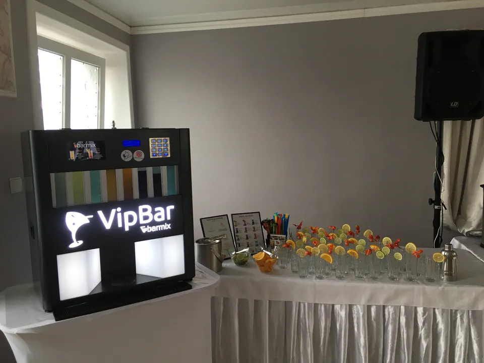 Automatyczny barman obok przygotowanych szklanek na białym stole
